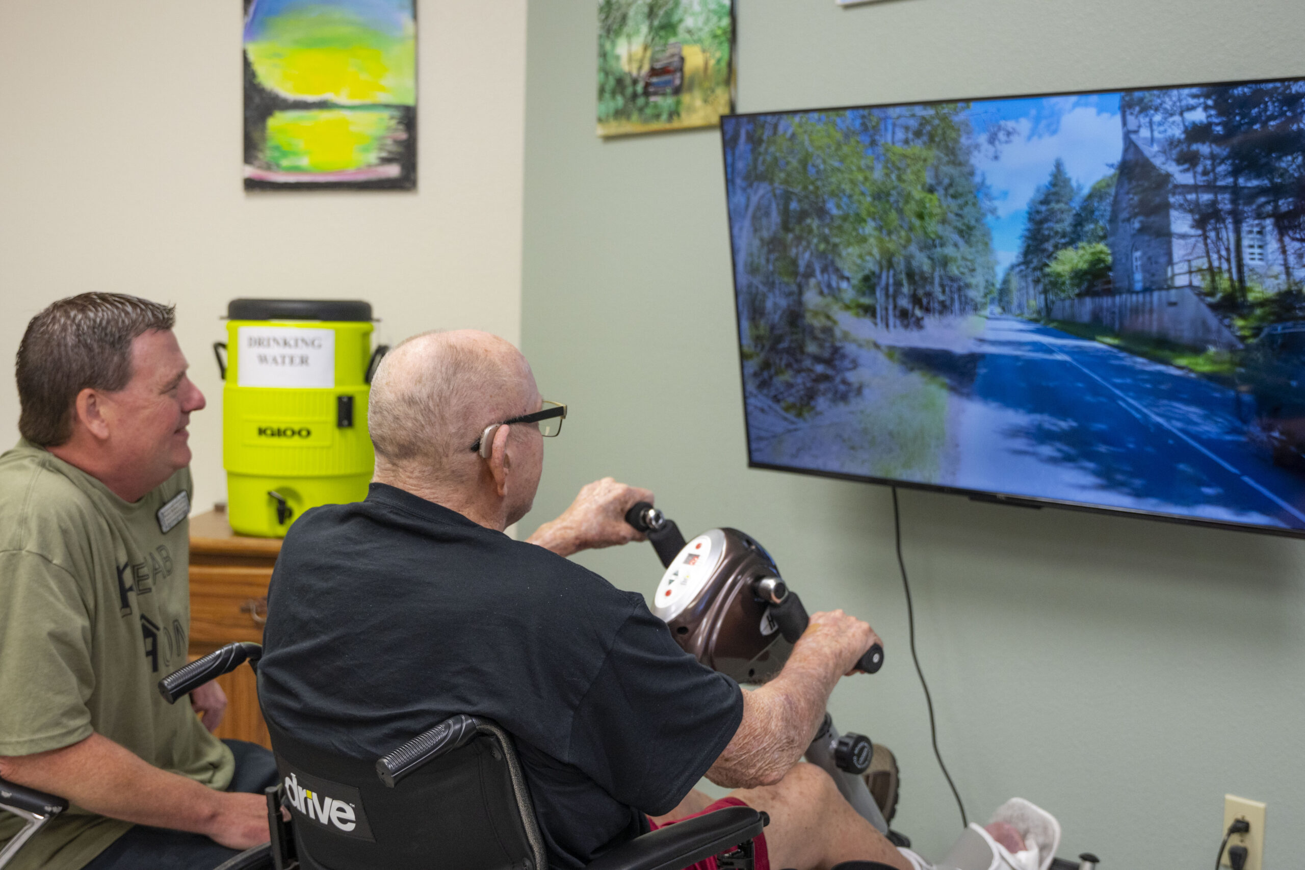 Male resident at Kent County nursing home is undergoing therapy with a therapist wokring out his arms and legs