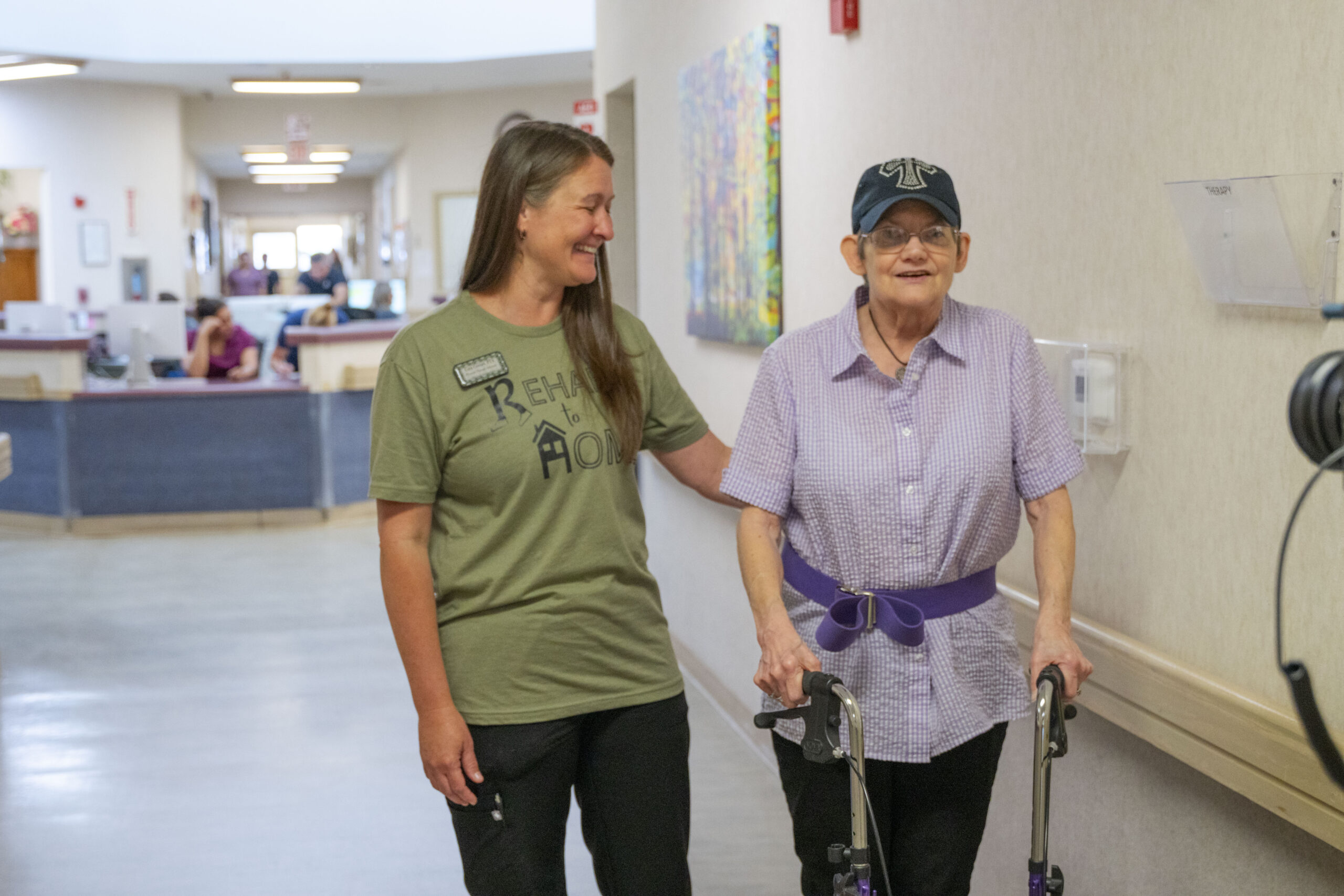 Resident and therapy staff member at Kent County Nursing Home in Jayton, TX, smiling and undergoing therapy session in hallway